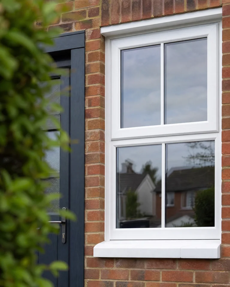 Detail of a white sash-style window beside an anthracite grey door